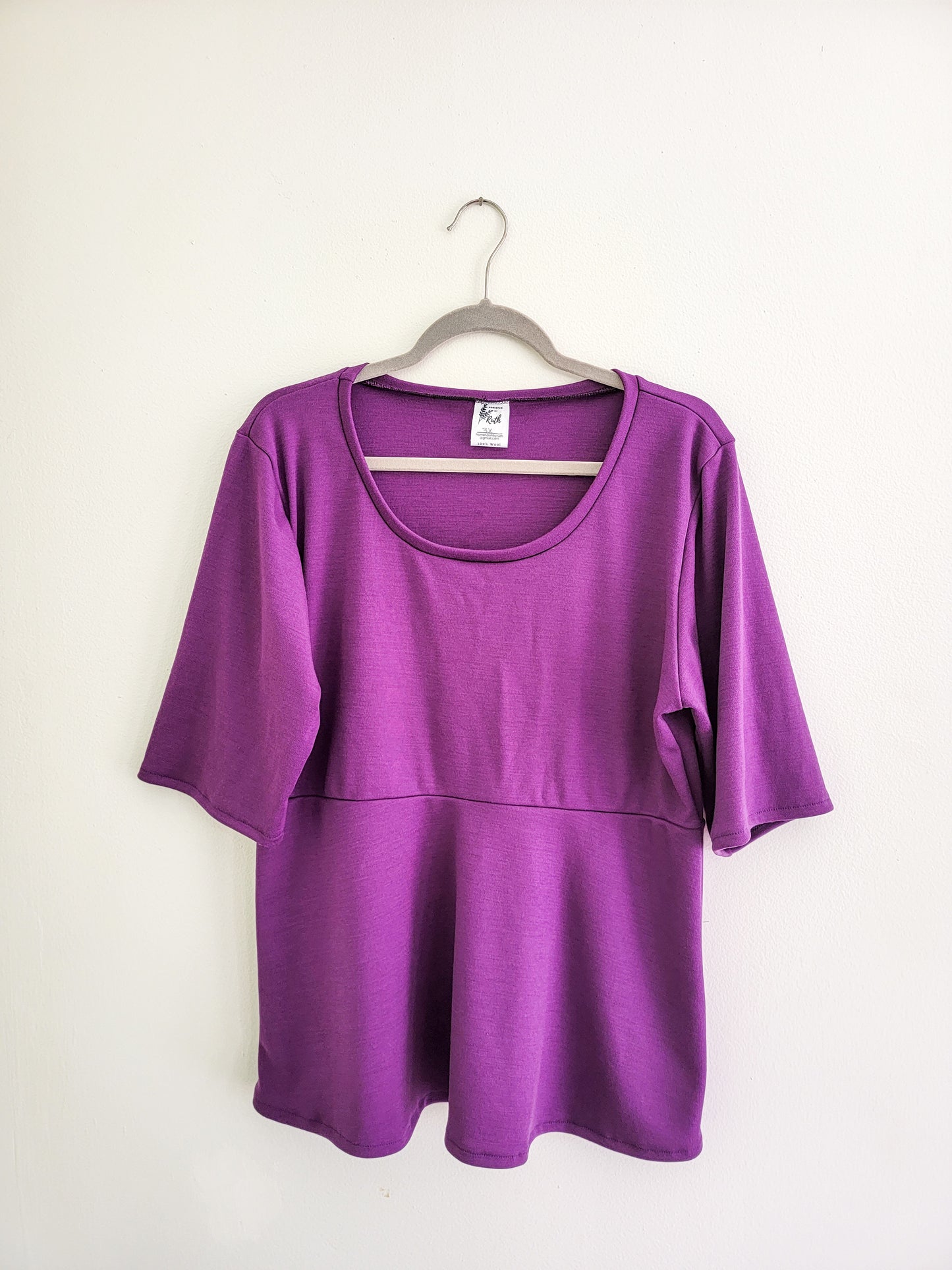 Women's Purple Wool Peplum hanging against a white wall